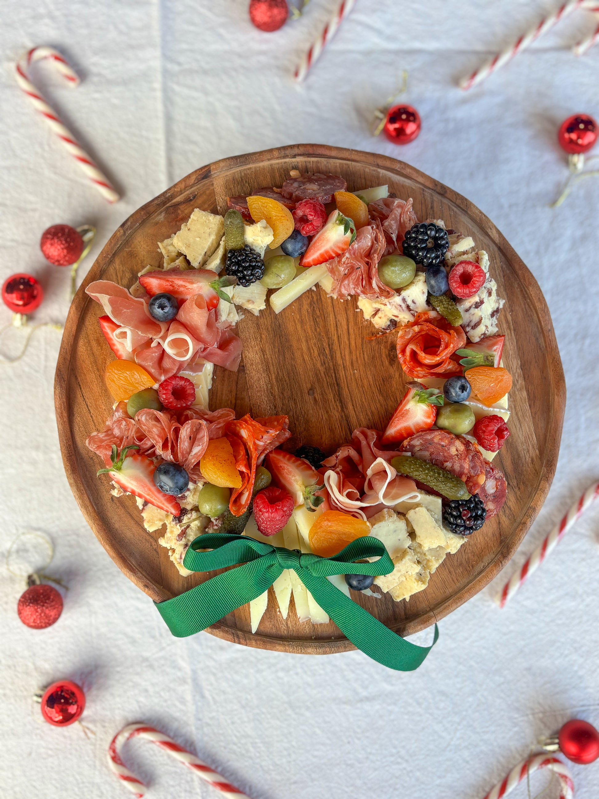A festive charcuterie & cheese wreath, with a variety of cheeses, charcuterie, antipasto and fresh fruit.