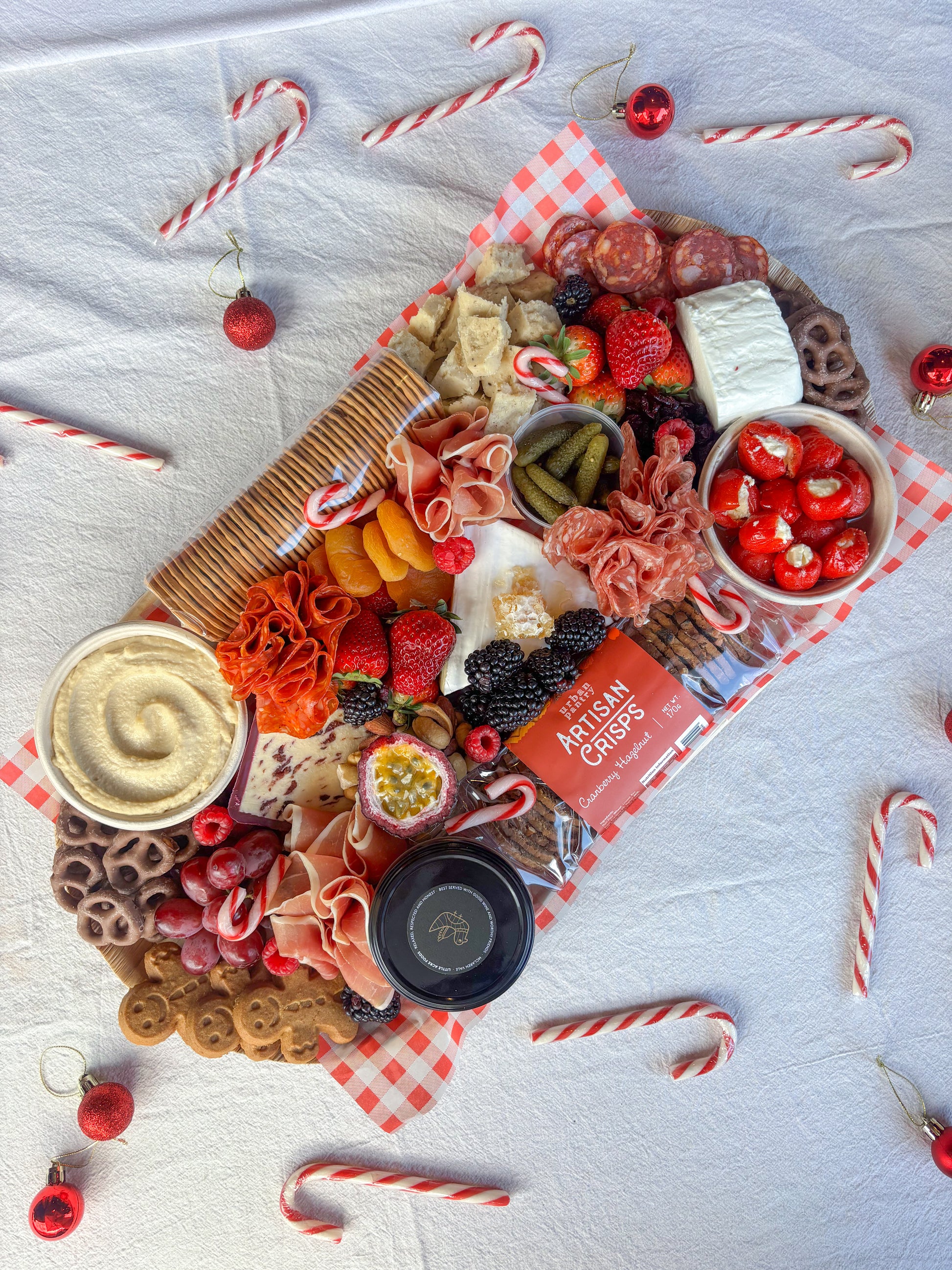Assorted charcuterie board with a variety of meats, cheeses, and fruits with candy canes and Christmas decorations.